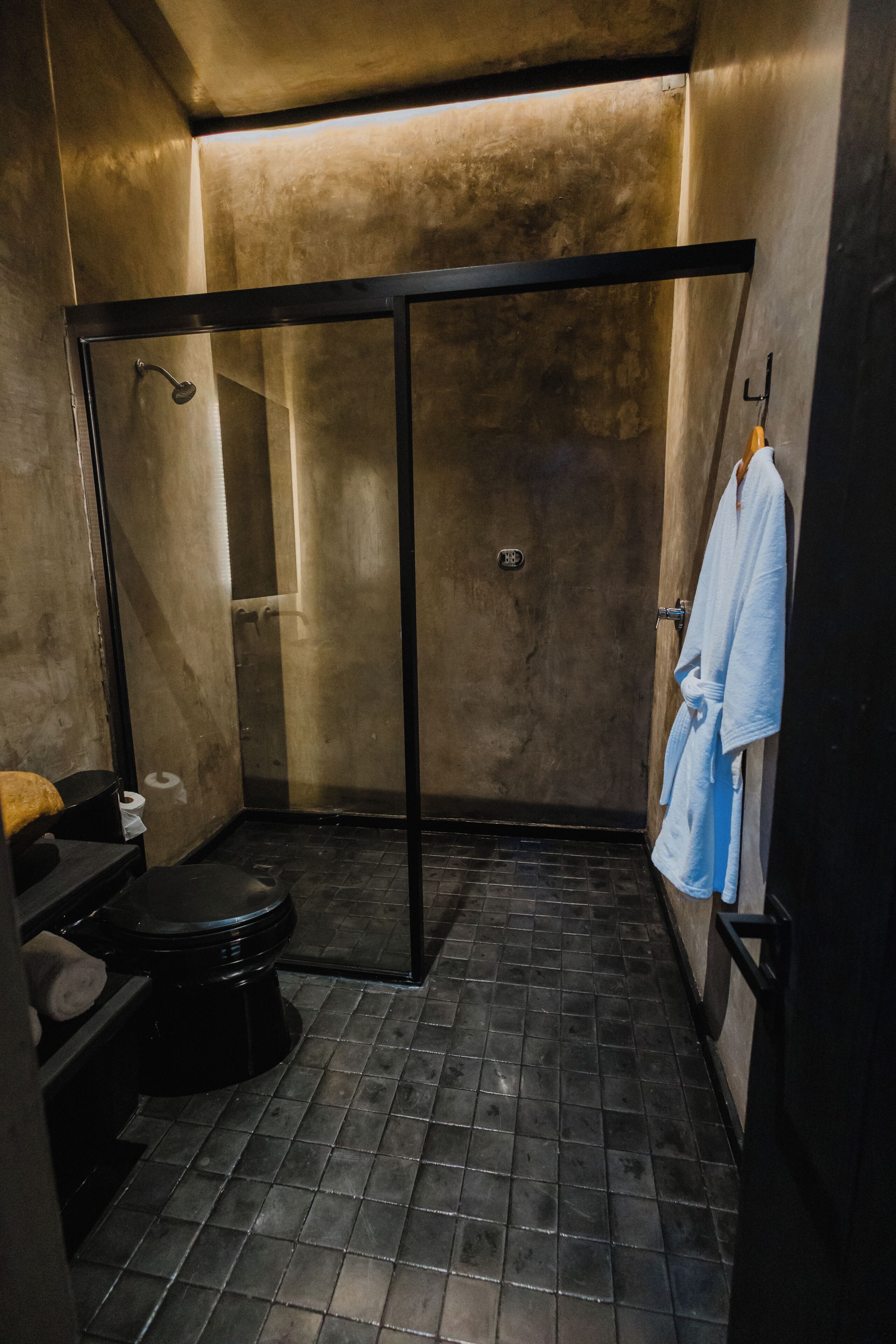 Un baño moderno y compacto con ducha, inodoro y perchero para toallas.