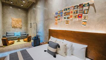 Una camera d'hotel moderna con un letto grande, un divano, un tavolino e una parete decorata con tessuti colorati.