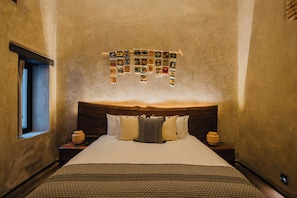 A hotel room with a large bed, a wooden headboard, and a wall decorated with a tapestry. - Casa Levonka (Oaxaca)