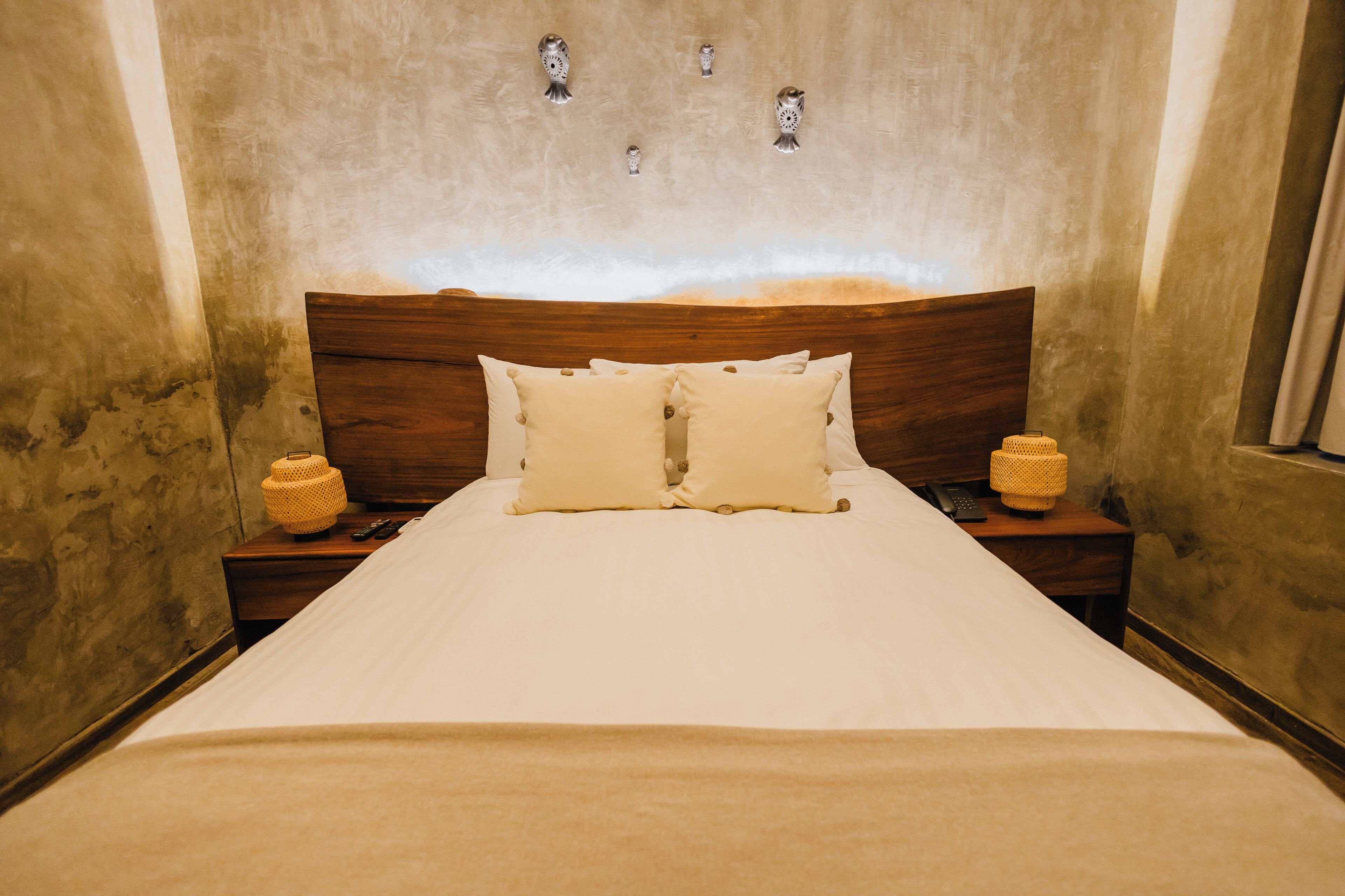 Una cama con cabecera de madera, dos mesitas de noche y dos lámparas.