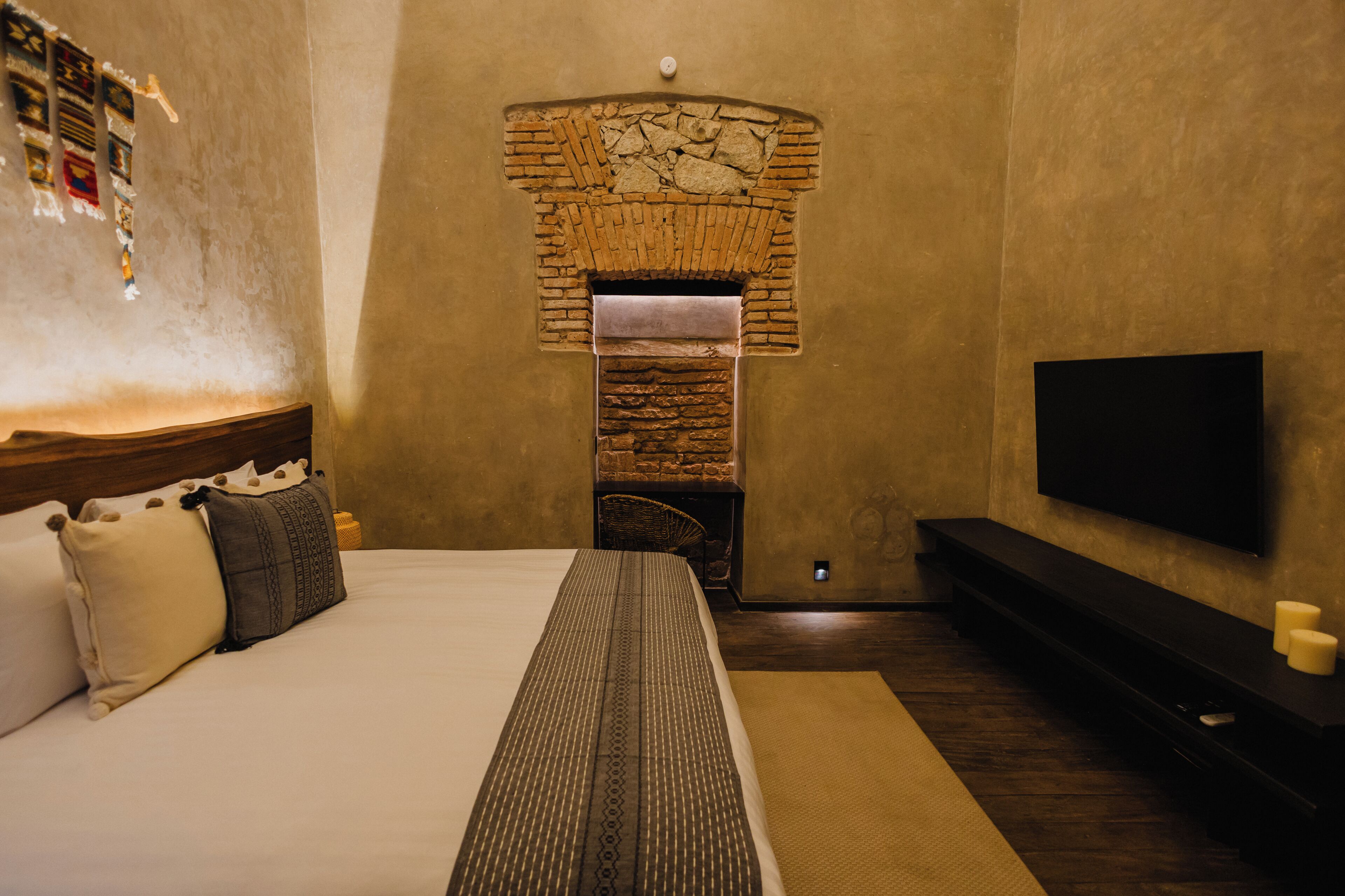 Habitación de hotel con una cama grande, una chimenea de piedra, un televisor de pantalla plana y un reloj de pared.