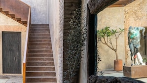 Una escalera que lleva a una puerta, una planta en maceta y una escultura.