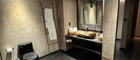 A modern bathroom with a black tiled floor, a toilet, a sink with a mirror, and a towel rack.