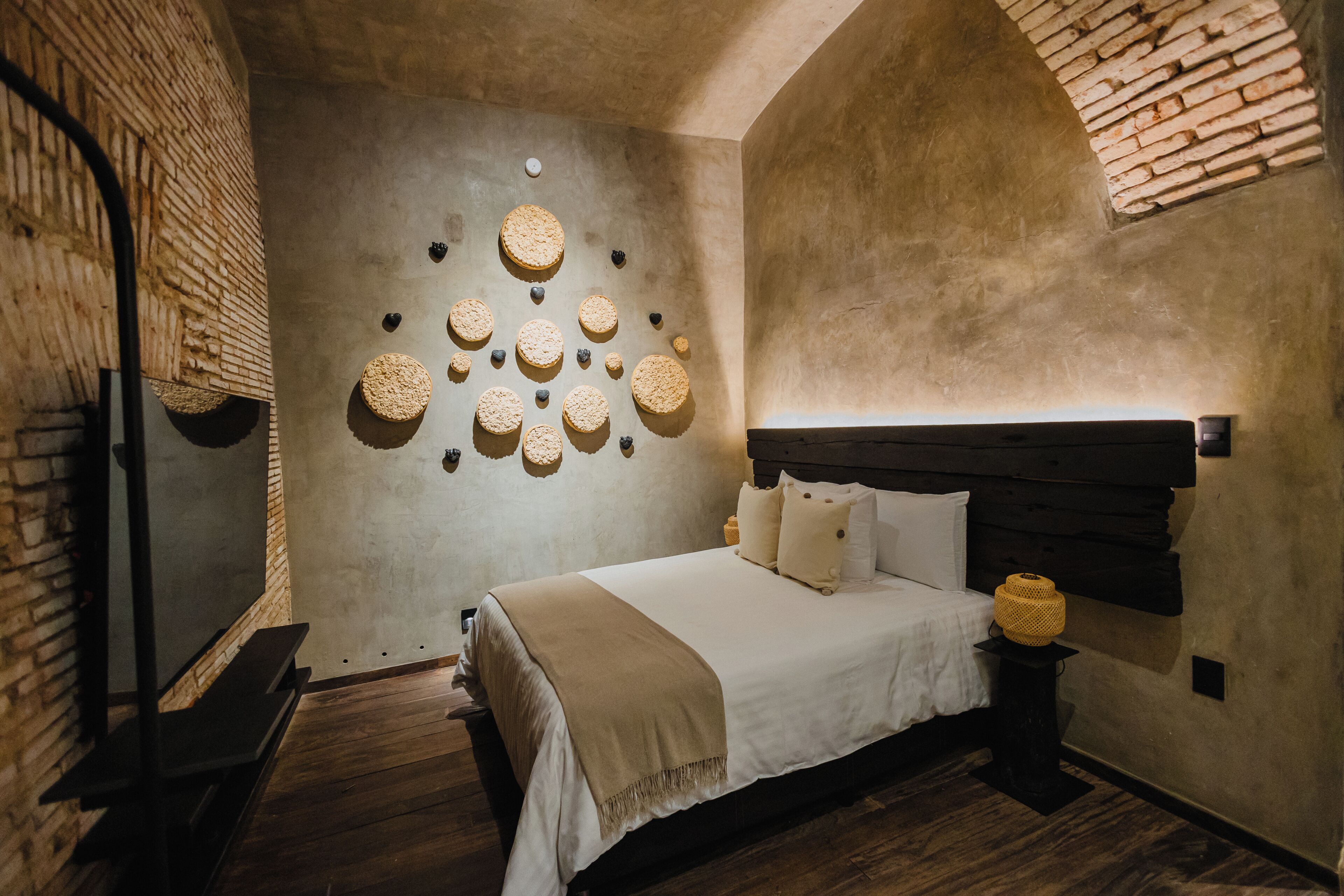 A bedroom with a bed, a headboard, a wall with circular decorations, and a brick wall.