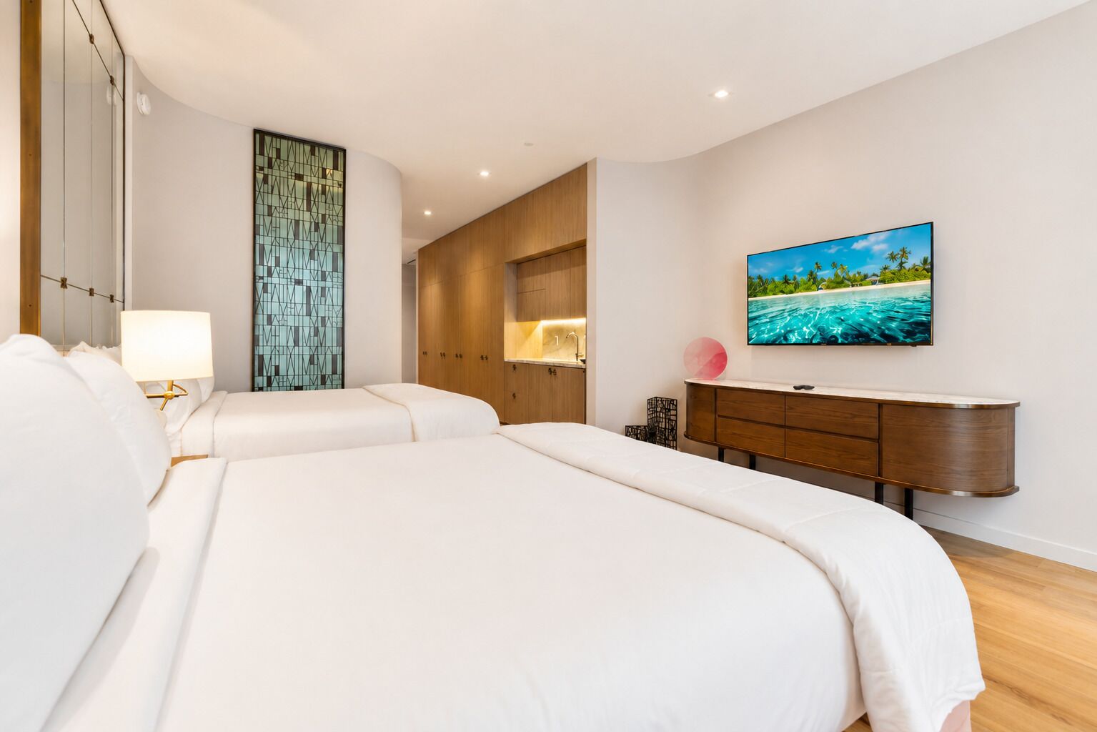 Une chambre d’hôtel avec deux lits, un téléviseur, une armoire en bois et une grande fenêtre.