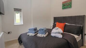 A bedroom with a bed, a window, a painting, and a wall socket.