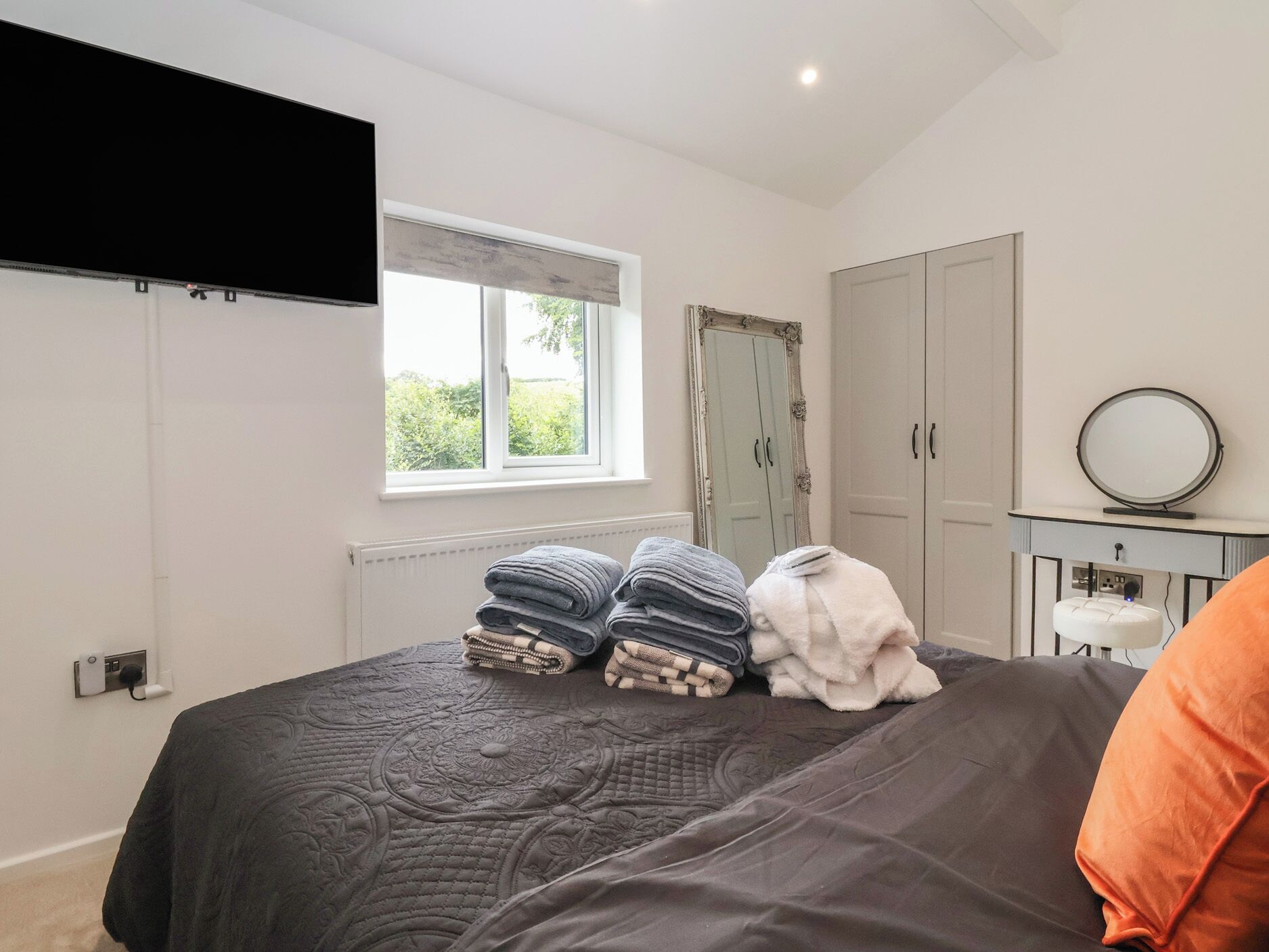 A bedroom with a bed, a window, a wardrobe, and a mirror.