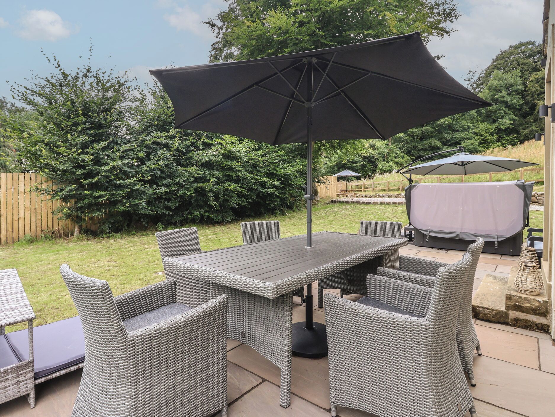 An outdoor patio with a table and chairs, a large umbrella, and a barbecue grill.