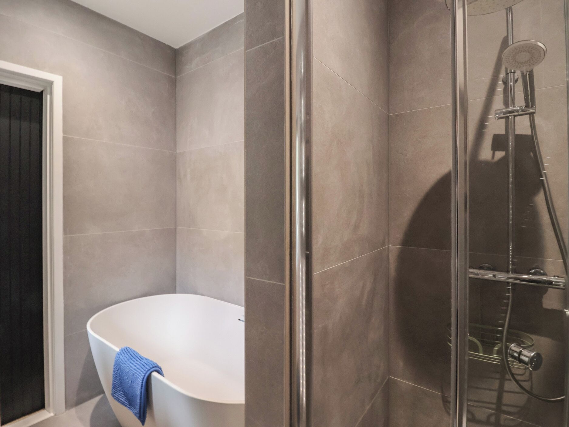 Une salle de bain moderne avec une baignoire sur pieds, une douche à parois de verre et une porte donnant sur une autre pièce.