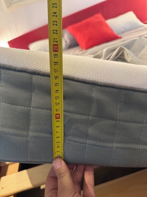 A hand holding a measuring tape against a sofa with a red and white cushion in the background. - Modern studio downtown Budapest, next to airport road, also for business trips (Budapest)