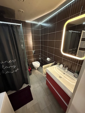 A modern bathroom with a shower curtain, toilet, and vanity with a mirror. - Modern studio downtown Budapest, next to airport road, also for business trips (Budapest)