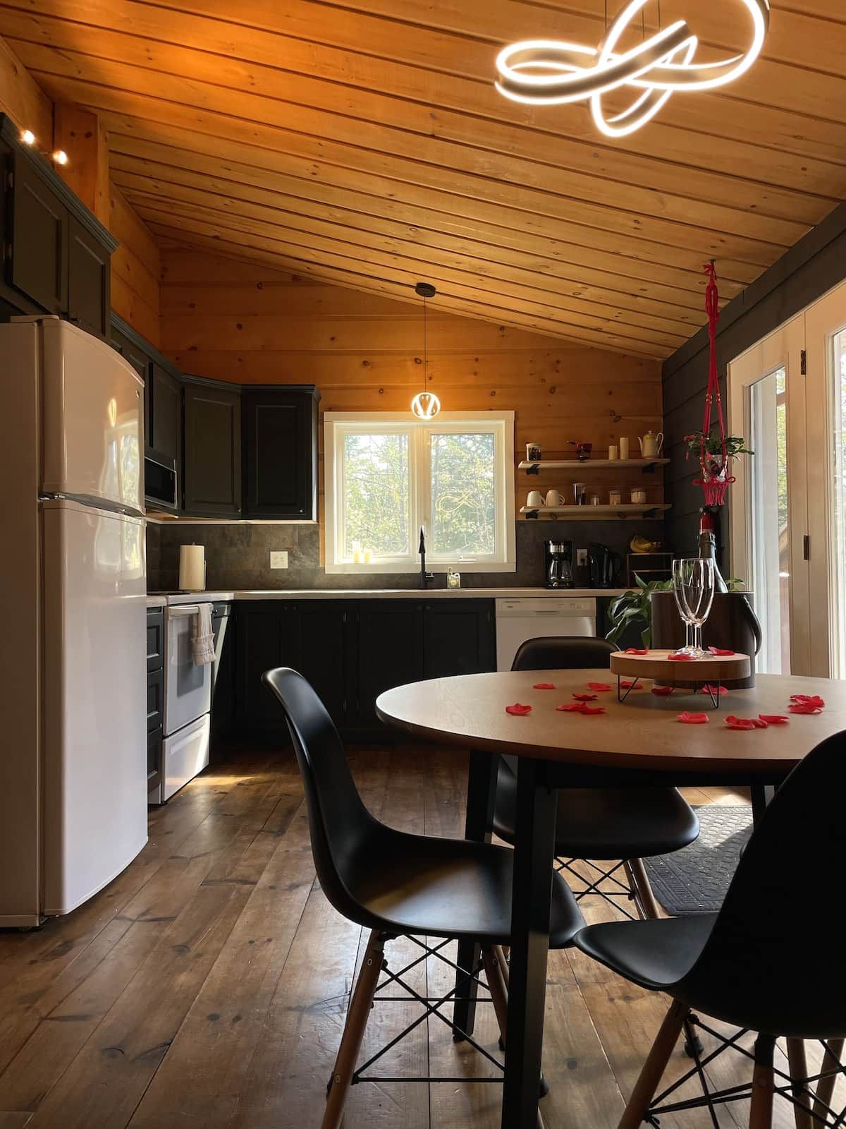 A wooden interior with a kitchen, dining area, and a large window.
