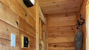 Un interno in legno con una porta, una lampada a parete e una borsa appesa.