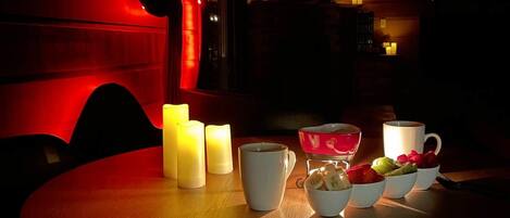 A dimly lit room with a round table, candles, and a red ambient light.
