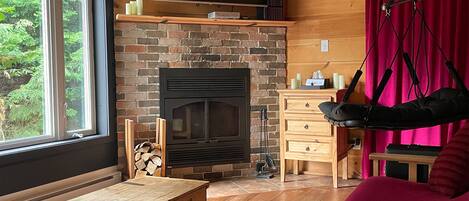 A cozy room with a fireplace, wooden furniture, and a large window.