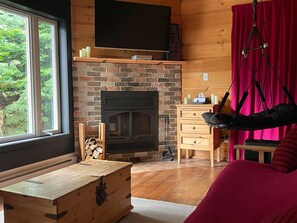 Ein gemütliches Zimmer mit Kamin, Holzmöbeln und einem großen Fenster.