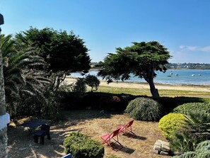 A beach view with a clear sky, a sandy beach, and a few boats in the water.
