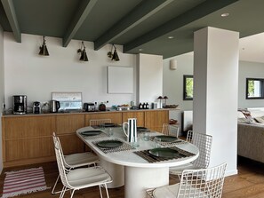 Una cocina moderna con una isla central, armarios blancos e iluminación colgante.