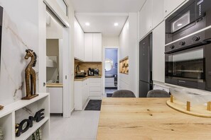 Een moderne keuken met een inbouwoven, een eethoek met een houten tafel, en een keukeneiland.