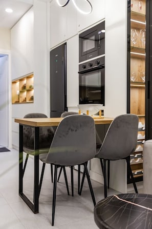 Een moderne keuken met een eethoek, met een houten tafel, twee grijze stoelen en een zwarte oven.