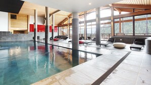 Ein Hallenbad mit Liegestühlen und Blick auf den Wald.