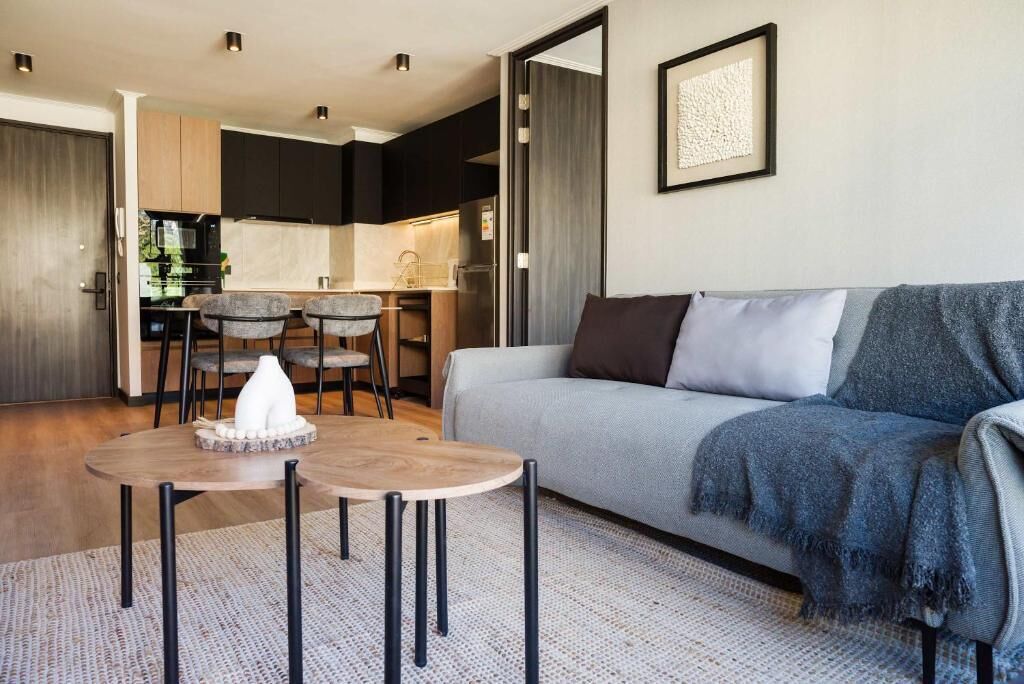A modern living room with a sofa, a coffee table, and a dining area with chairs.