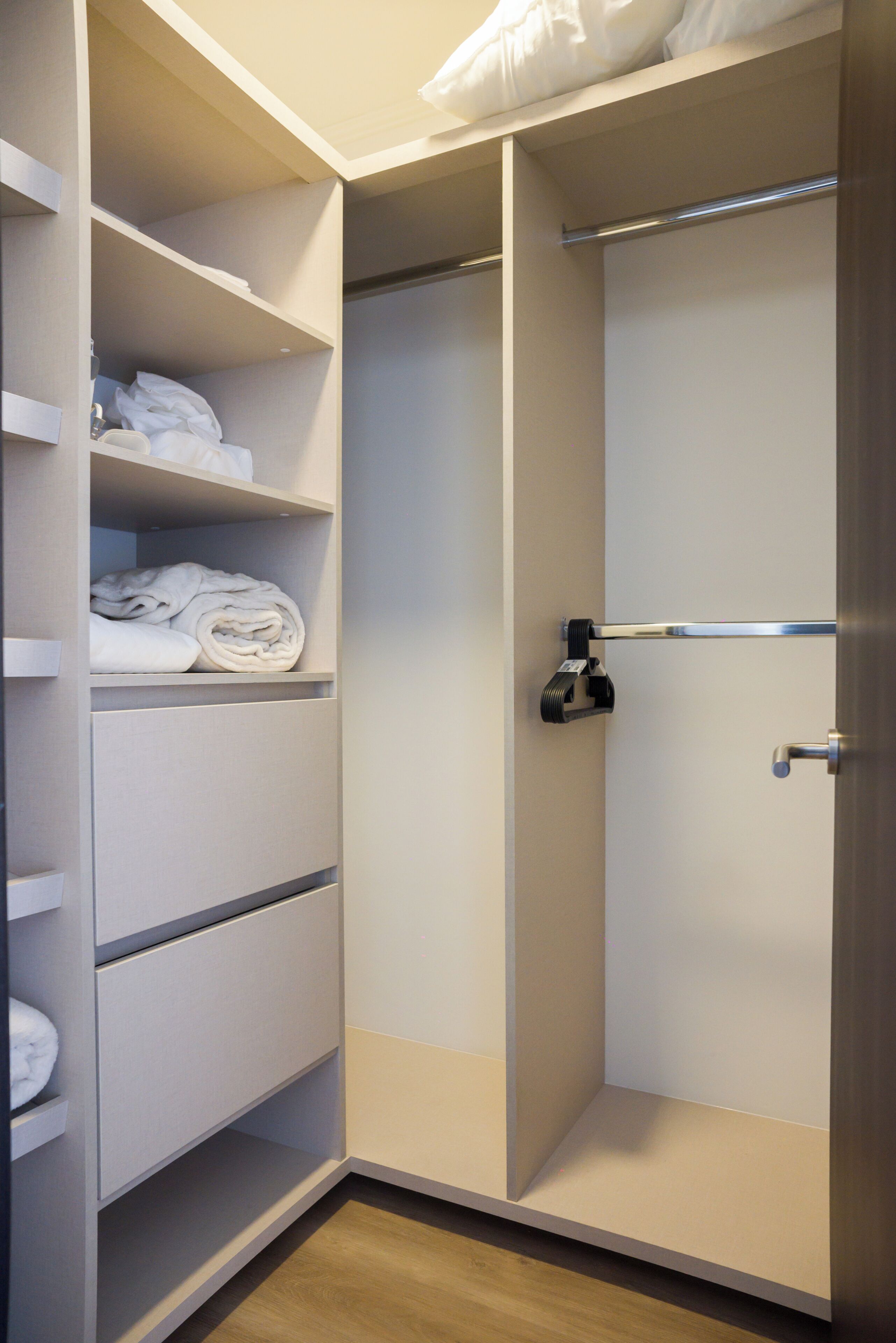 Ein begehbarer Kleiderschrank mit Regalen, einer Kleiderstange und einer Tür mit Griff.