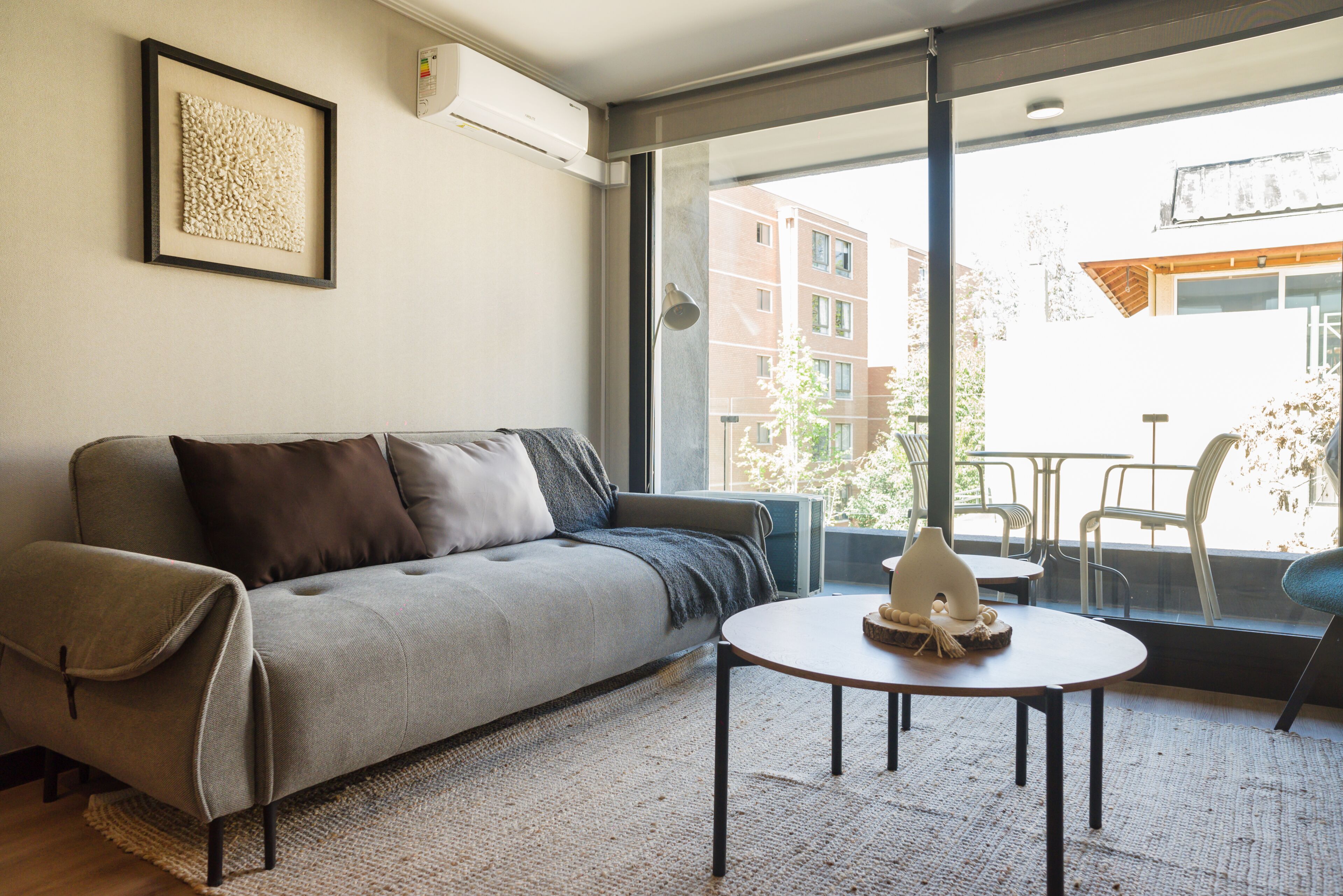 A modern living room with a sofa, a round table, and a large window.