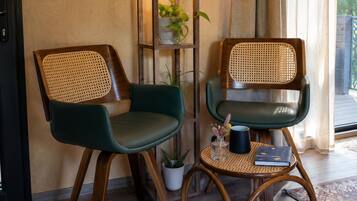 Two wicker chairs with wooden legs, a small round table with a woven base, and a tall floor lamp with a textured shade.