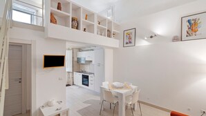 Eine moderne Wohnung mit Essbereich, Küche und einem Schlafzimmer im Zwischengeschoss mit Balkon.