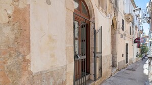 Eine enge Gasse mit einem Gebäude, das eine große Holztür und Metallgitter, Steinwände und ein Schild für 'Andres & Co.' zeigt.