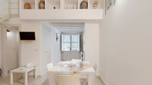 Ein modernes Interieur mit Essbereich, einem an der Wand befestigten Fernseher und einer Treppe, die zu einer oberen Ebene führt.