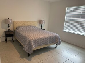 A bedroom with a bed, two bedside tables, and a window with blinds. - Charming Pet-Friendly 4BR Cape Coral, minutes from Pine Island and Yacht Club! (Cape Coral)