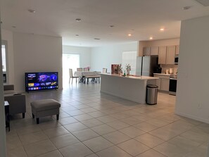 A modern kitchen with white cabinets, a stainless steel refrigerator, and a dining area with a table and chairs. - Charming Pet-Friendly 4BR Cape Coral, minutes from Pine Island and Yacht Club! (Cape Coral)