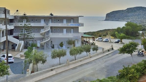 Un edificio de varios pisos con balcones, una escalera y un letrero que indica 'Falassarna beach'.