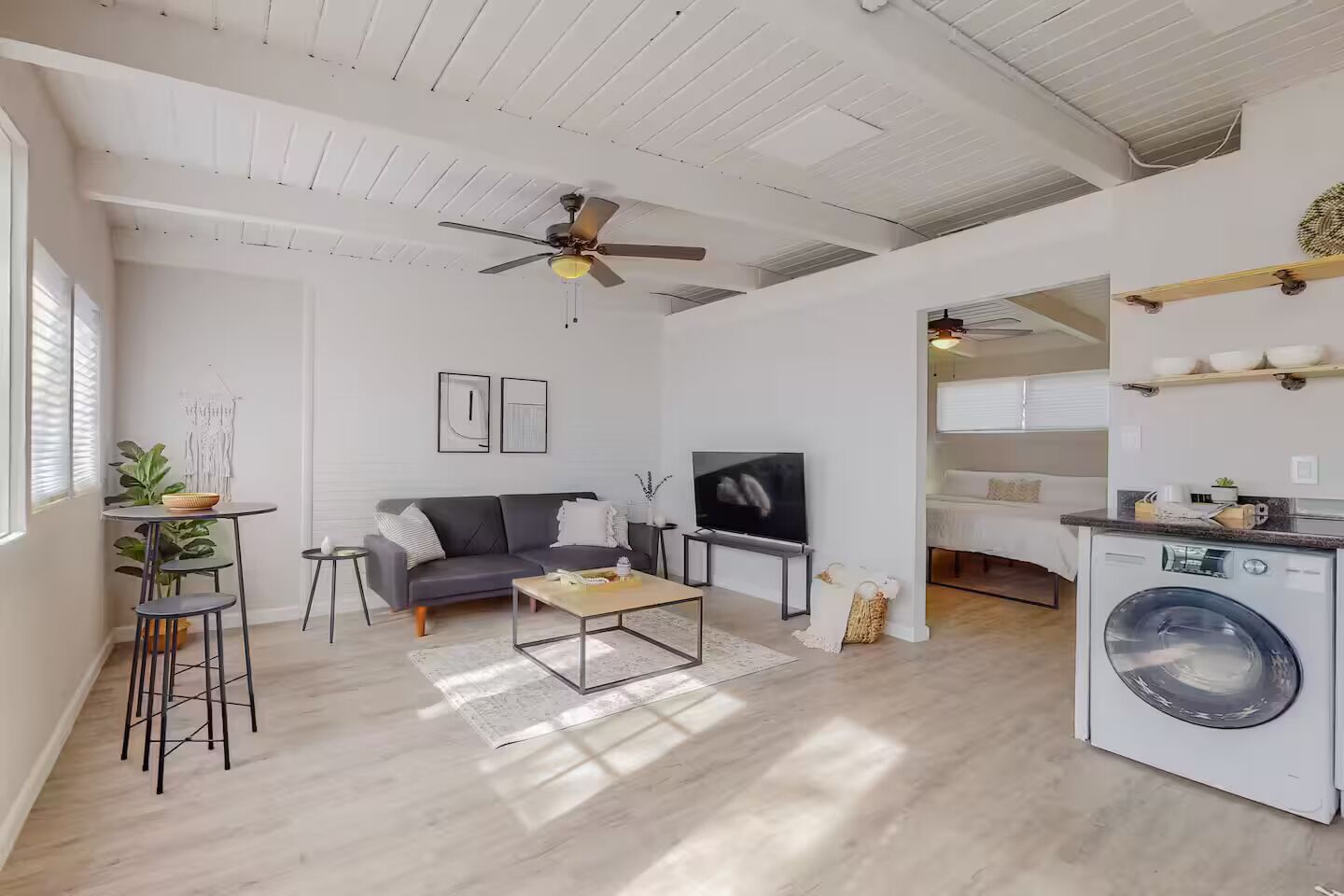 Ein modernes Wohnzimmer mit Sofa, Couchtisch, Fernseher und Waschmaschine – alles auf engem Raum.
