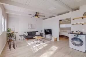A living room with a sofa, coffee table, TV, and a washing machine. - Remodeled Courtyard Apt w/King Bed, In-Unit W&D (Albuquerque)