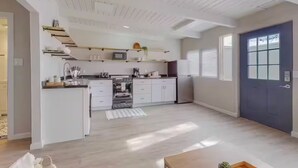 Een moderne keuken met witte kastjes, een ingebouwde oven en een magnetron.