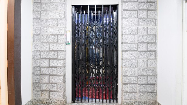 A door with a metal gate, set in a wall with a textured pattern.