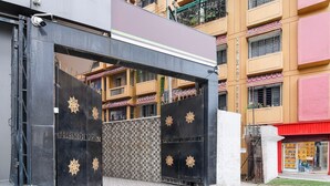 A gated entrance with a metal gate and decorative elements, leading to a building with multiple balconies and a visible storefront.