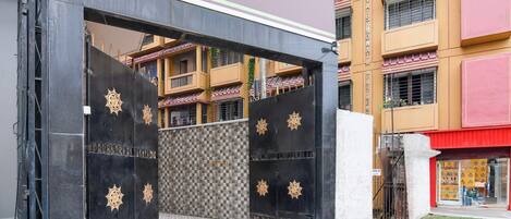 A gated entrance with a metal gate and decorative elements, leading to a building with multiple balconies and a visible storefront.
