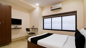 Une chambre d’hôtel équipée d’un lit, d’un bureau, d’une chaise, d’une télévision et d’un appareil de climatisation.