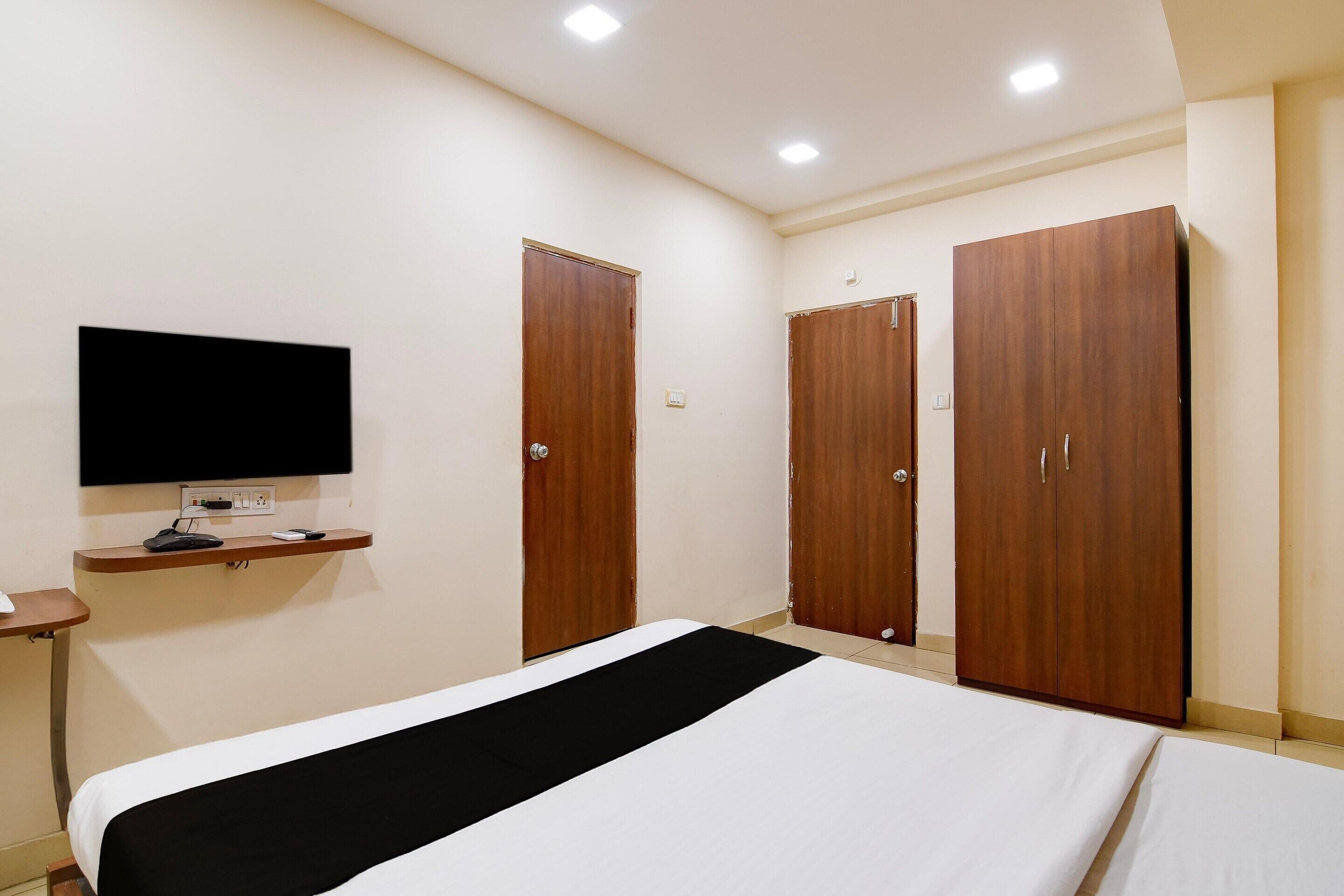 Hotellihuone, jossa on sänky, seinälle asennettu televisio ja kaksi vaatekaappia.