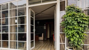 Una entrada de edificio con puertas de vidrio, piso de baldosas y una planta en maceta.