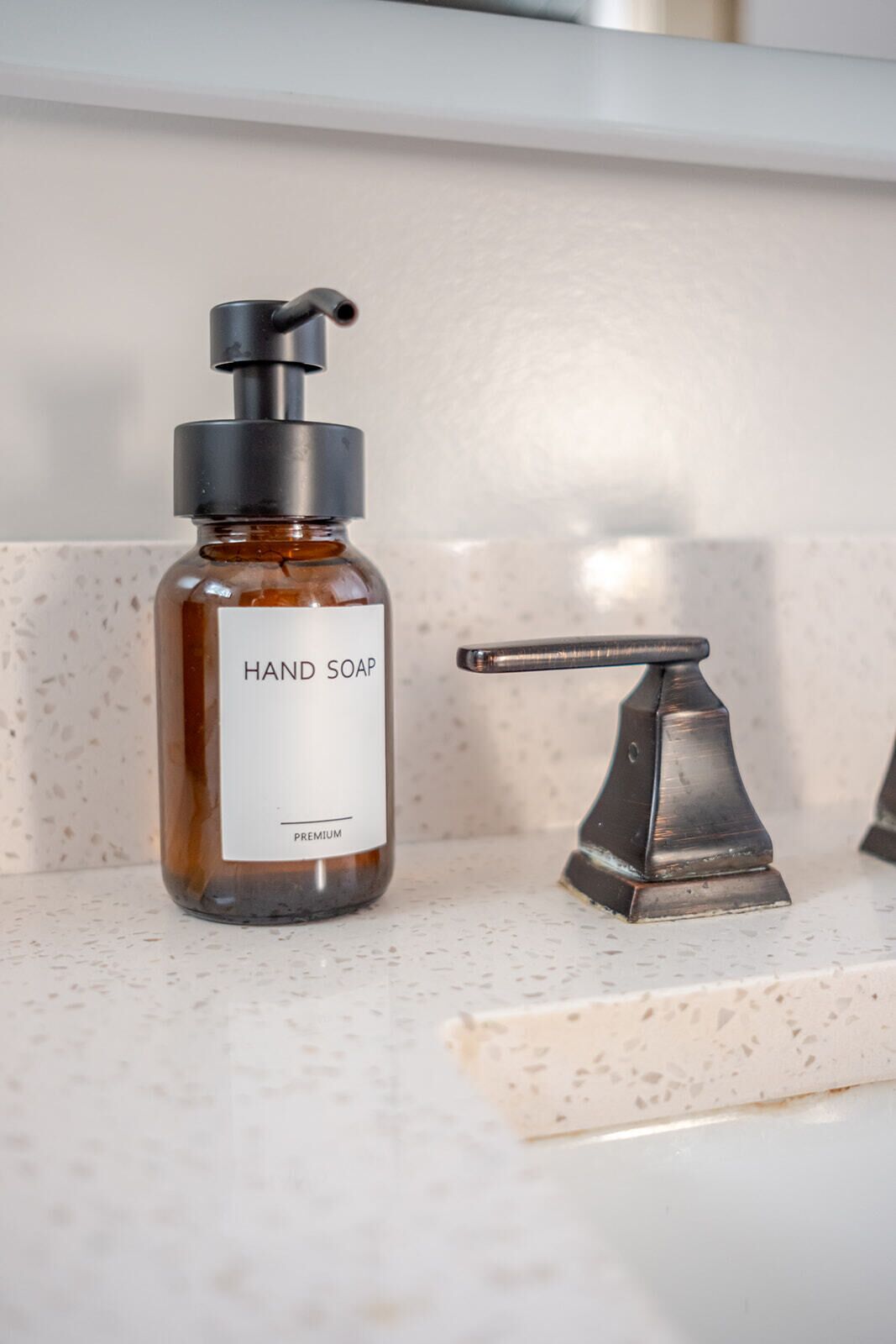 A hand soap bottle with a pump dispenser on a speckled countertop.