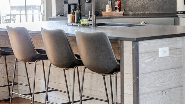 A kitchen with a central island, bar stools, pendant lighting, and a coffee machine. - Stylish 3BR in Fountain Square Pool, Firepit, Bocce Court + Golden Tee (Indianapolis)