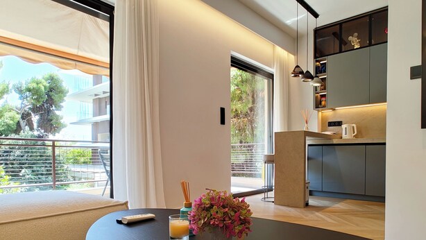 A modern living room with a sofa, a table with a remote control, a candle, and a welcome brochure. - Designer Flat in Voula Center (Voula)