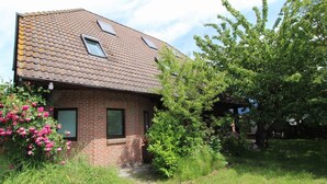 Ein Haus aus Ziegelsteinen mit einem geneigten Dach, zwei Dachfenstern und einer kleinen Veranda.