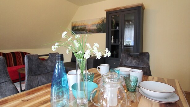 Una mesa de comedor con diferentes vasos y un florero con flores.
