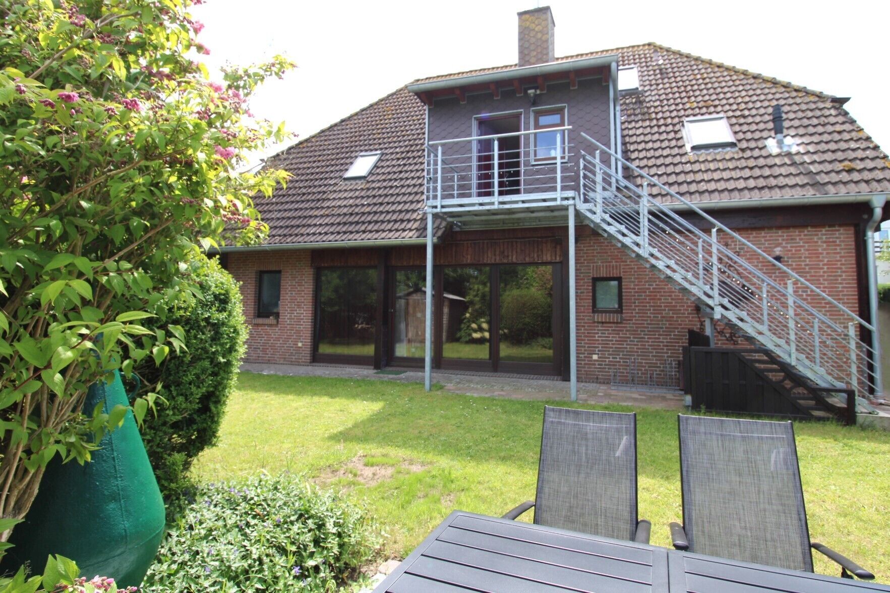 A two-story house with a covered patio, a staircase, and a large window.